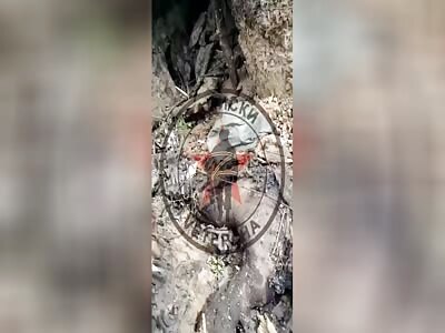 Russian walking in a trench full of burned Ukrainian corpses