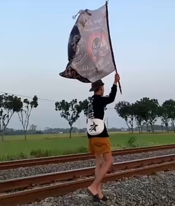 Man Carrying Flag Next to Train Tracks Is Struck by Train