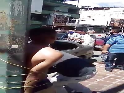 Street justice, thief tied up to pole.